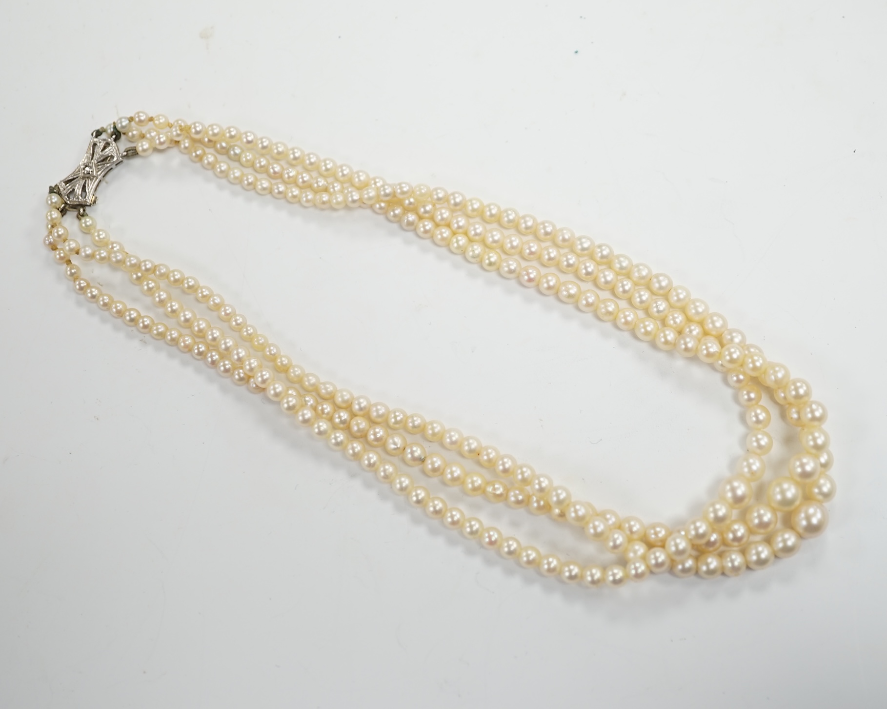 A triple strand graduated cultured pearl choker necklace, with diamond chip set 9ct white gold clasp, 38cm, in a Harrods box, together with some loose beads.